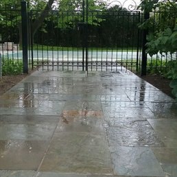 Concrete Patio & Gate — Wet concrete patio finish with black gate installation.