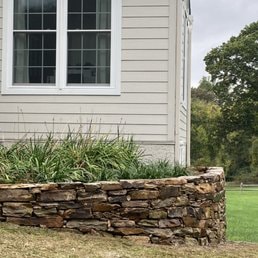 Stone Wall & Planter — Stone wall planter beside house windows.